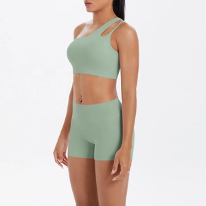 Detail of one-shoulder yoga bra and high-waisted shorts in sage green fabric