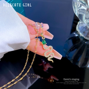Macro detail of gold snake pendant necklace with green drop gemstone and micro-inlaid stones