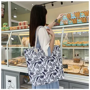 Detail of printed canvas tote bag featuring tropical parrot pattern and rope handles