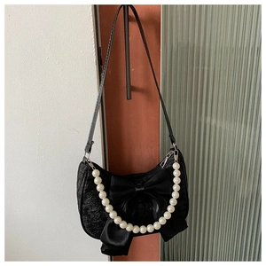 Detail of black jacquard shoulder bag with satin bow and pearl bead chain strap