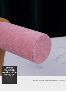 Macro detail of the soft pink velvet surface and natural wood stand of the bracelet holder