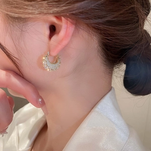 Close-up of gold-plated C-shaped earrings with micro-pave cubic zirconia on a model