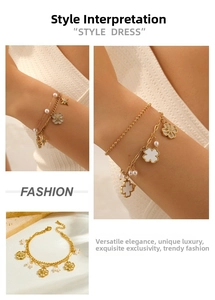 Detail of gold double-layer bracelet with pearls, flower and star pendants on a warm background