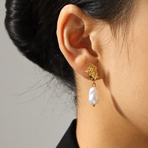 Gros plan détaillé d'une femme portant des boucles d'oreilles vintage en or 18k et perle