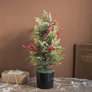 Mini Christmas tree with red berries and artificial snow in black pot for festive decor