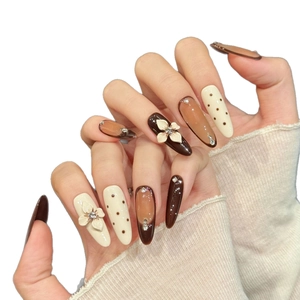 Brown cat-eye press-on nails with 3D floral accents and rhinestones on hands