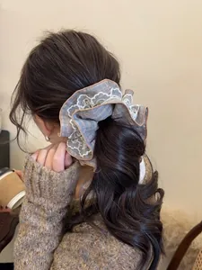 Close-up of a blue plaid scrunchie with white lace edges on a woman's ponytail