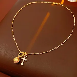 Collana lunga dorata con pendente a croce di strass e ciondolo a sfera rotonda traforata