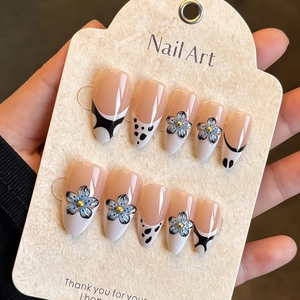 Faux ongles French avec fleurs 3D bleues et pois noirs sur une carte de présentation