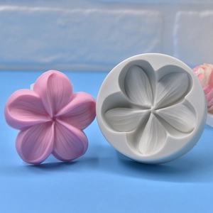White silicone 5-petal flower mold with pink cherry blossom craft piece on blue table