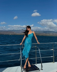 Blue one-shoulder chiffon maxi dress with slit flowing naturally on a luxury yacht