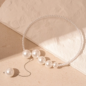 Détail d'un collier de perles vintage avec pampille longue et pendentif géométrique