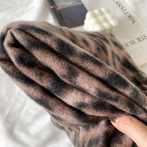 Close-up of soft cashmere-like fabric featuring a classic brown and black leopard print pattern