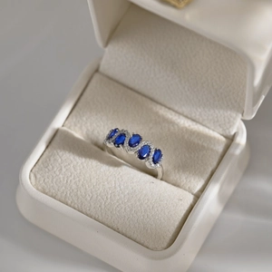 Close-up of S925 silver ring featuring five oval blue zircons in a white jewelry box