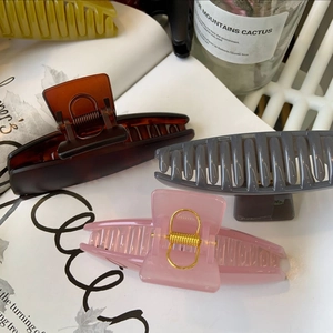 Detailed close-up of glossy resin hair claws in brown, gray and pink on a book