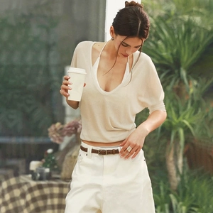 Chic beige deep V-neck knit top paired with white casual pants and a leather belt detail