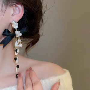 Close-up of bow knot pearl tassel earrings worn by a model in a warm setting