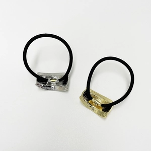 Minimalist elastic hair ties with gold and silver metal accents on white background