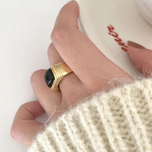 Detail of adjustable gold ring with oval black onyx gemstone on hand with sweater
