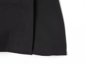 Detailed close-up showing the high-density black fabric texture of the formal suit trousers