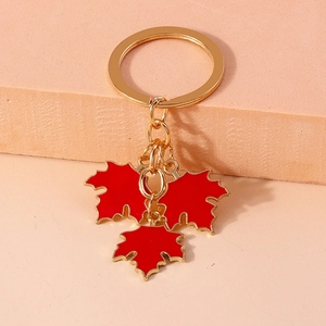 Detailed close-up of golden keychain featuring three vibrant red maple leaf charms