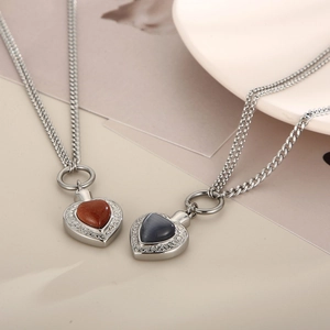 Détail de pendentifs en cœur avec pierres œil de chat sur des chaînes cubaines en acier