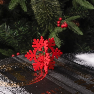 Flocon de neige 3D en bois rouge avec motifs de cloches sur fond de sapin de Noël enneigé