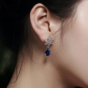 Close-up of 925 silver flower earrings with teardrop blue sapphire and white zircon gems