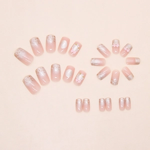 Detail of pink cat-eye press-on nails with 3D bows, pearls and checkered patterns