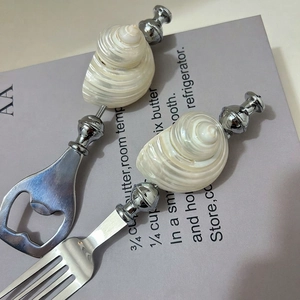 Detail of stainless steel fork and bottle opener with natural conch shell handle design
