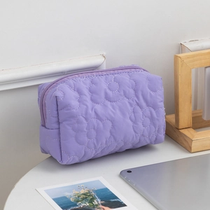 Close-up of purple quilted toiletry bag with large flower pattern on a minimal desk
