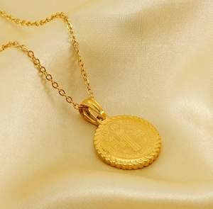 Macro shot of 18K gold plated Saint Benedict medallion necklace with rope border on silk