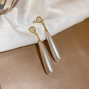 Detailed view of long water-drop pearl earrings with elegant golden metal hooks