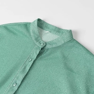 Vue détaillée d'une chemise à paillettes vertes avec col officier et boutons assortis