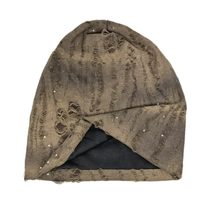 Détail du bonnet en maille style grunge avec paillettes argentées et finitions déchirées