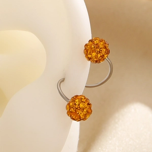 Macro shot of amber crystal Shamballa ball earring on a white silicone ear model