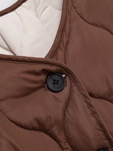 Detail of dark brown quilted fabric with black button and cream lining on winter jacket