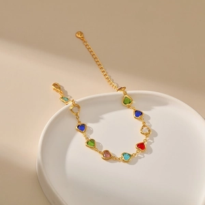 Detail of colorful heart-shaped gems on a gold chain bracelet with a lobster clasp