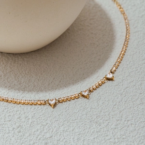 Elegant gold-plated heart necklace with cubic zirconia paving on a minimalist white texture