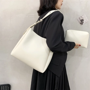 Detailed side view of a large white faux leather tote bag and matching inner pouch