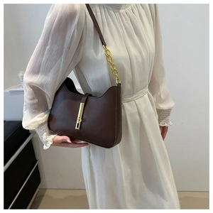 Detailed view of the dark brown leather shoulder bag with golden chain and clasp