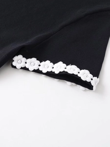 Detail of the black knit fabric with exquisite 3D white floral lace trim on the sleeve