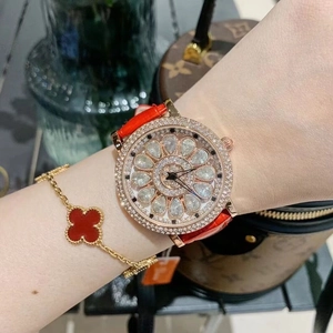 Close-up of luxury rotating diamond watch with red strap and matching clover bracelet