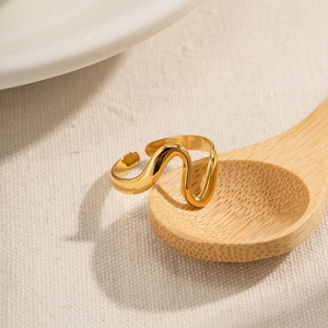Elegant gold wave-shaped adjustable open ring with a polished mirror finish on wood