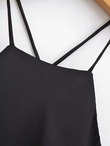 Detail of cross straps and V-neckline on a black satin texture summer slip dress