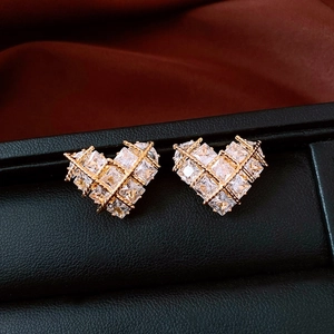 Macro view of 18k gold plated heart studs with zircon stones on dark leather texture