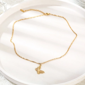 Minimalist gold butterfly pendant necklace elegantly displayed on a white ceramic tray