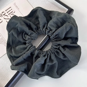 Detail of dark green fabric scrunchie on a beige tray for elegant hair styling