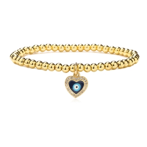 Golden beaded bracelet featuring a heart-shaped evil eye pendant with sparkling crystals