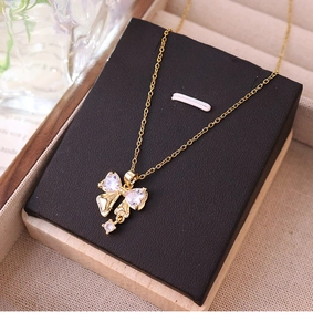 Détail d'un collier pendentif nœud doré avec zircones étincelants sur support noir